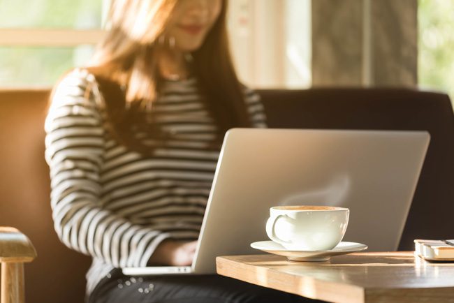 How Online Recovery Communities Can Help You Stay Sober - young woman with laptop and coffee at table
