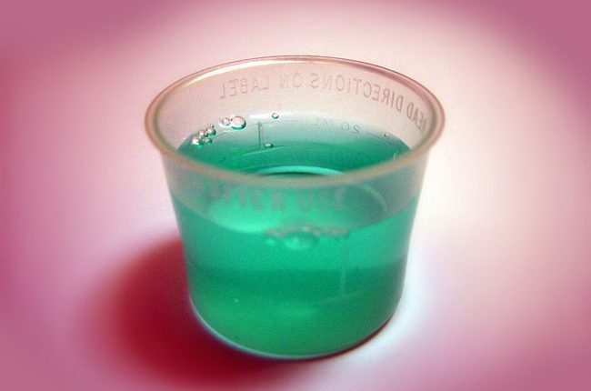 medicine cup of green liquid - medications