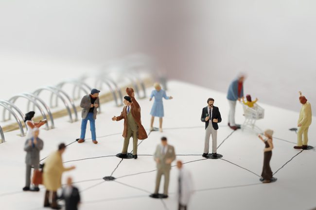 miniature figures set on paper representing social networking - social distancing